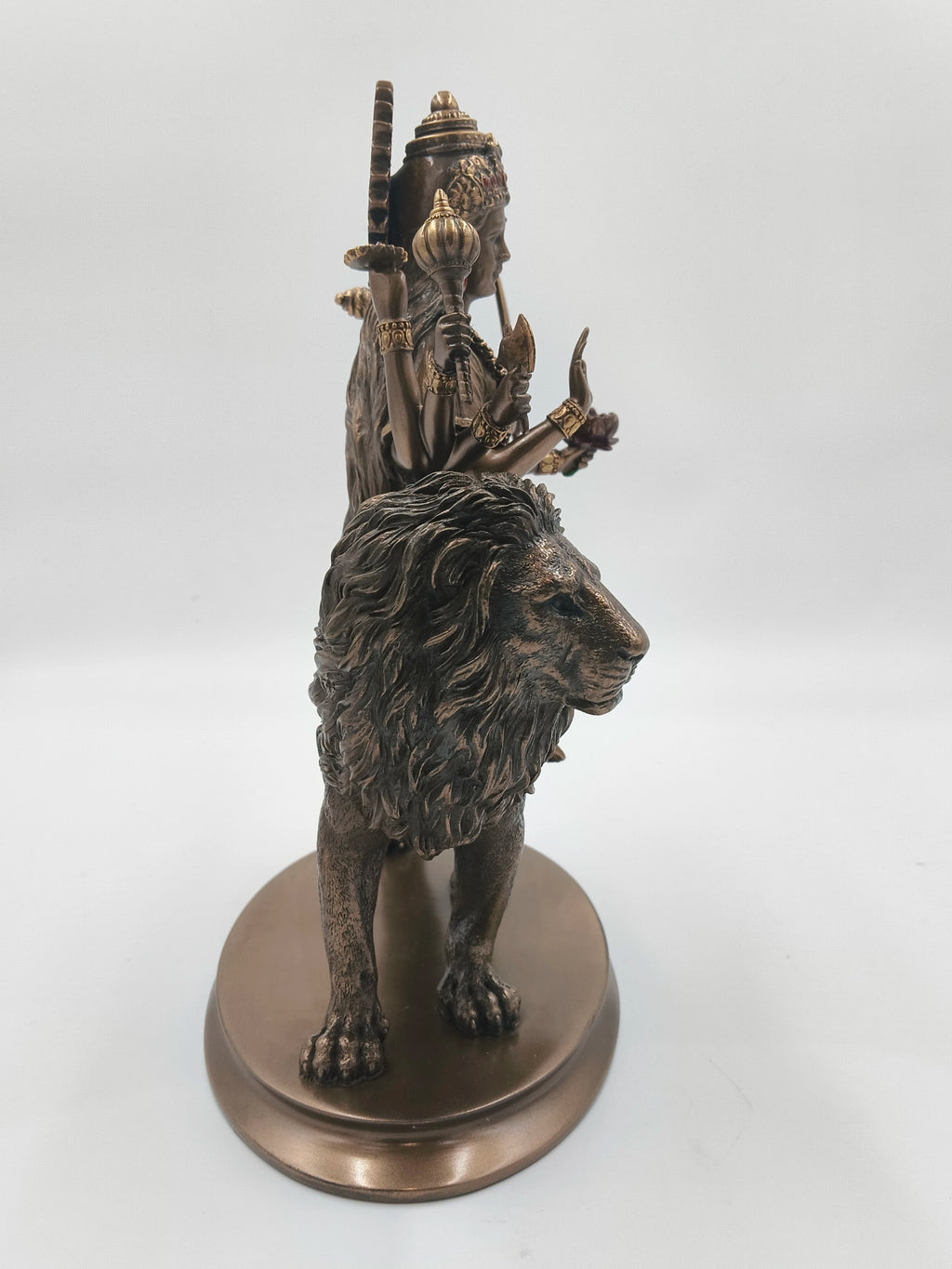 Side view of polyresin statue of Durga Maa holding weapons, riding lion