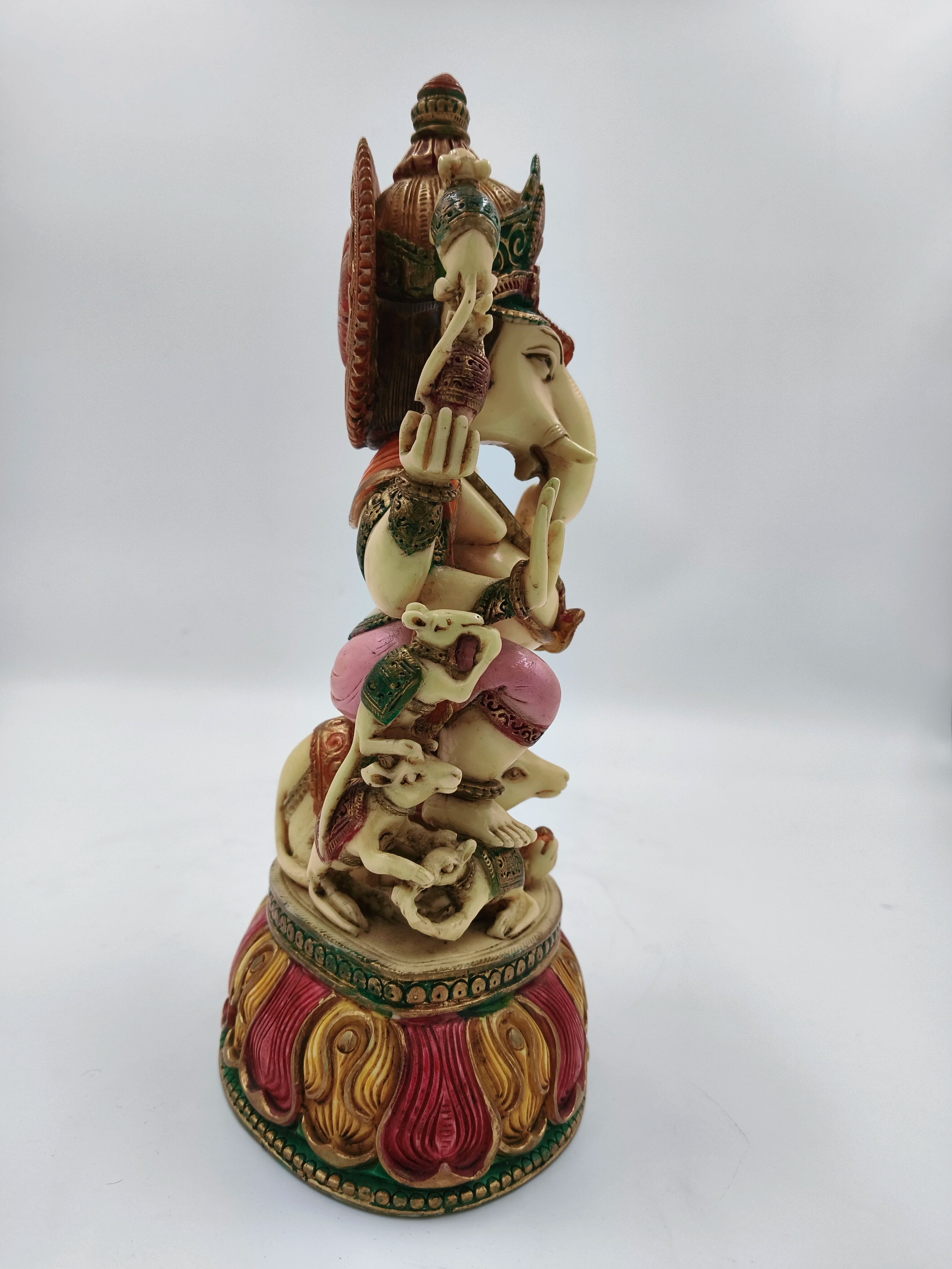 Side view of large polyresin Ganesh statue seated on rat with detailed colorful base