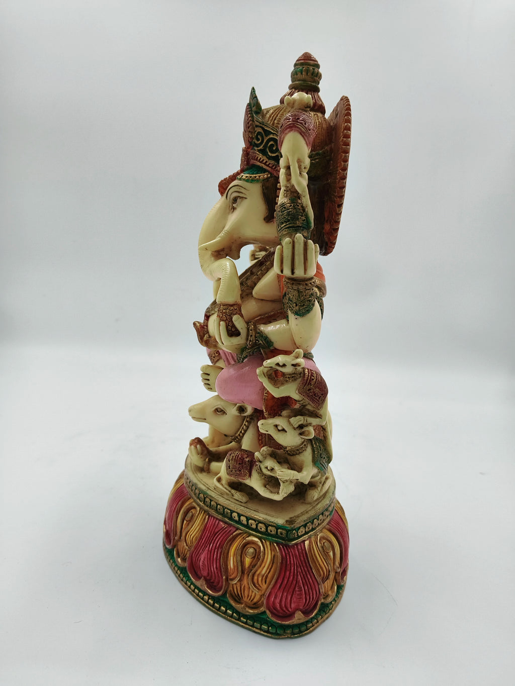 Side view of large polyresin Ganesh statue seated on rat with colorful base
