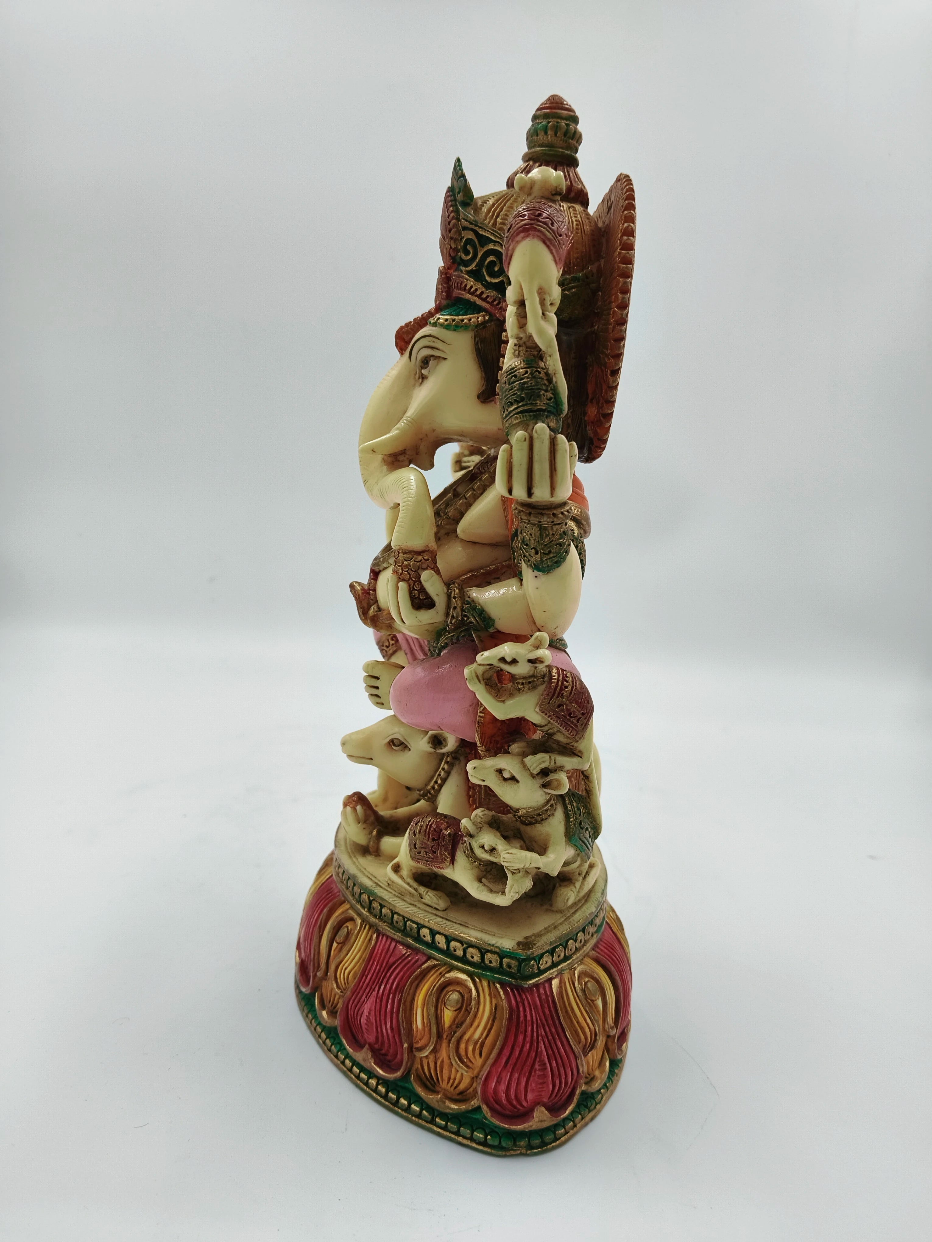 Side view of large polyresin Ganesh statue seated on rat with colorful base