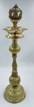 Large brass traditional oil lamp with intricate carvings and Ganesha figure