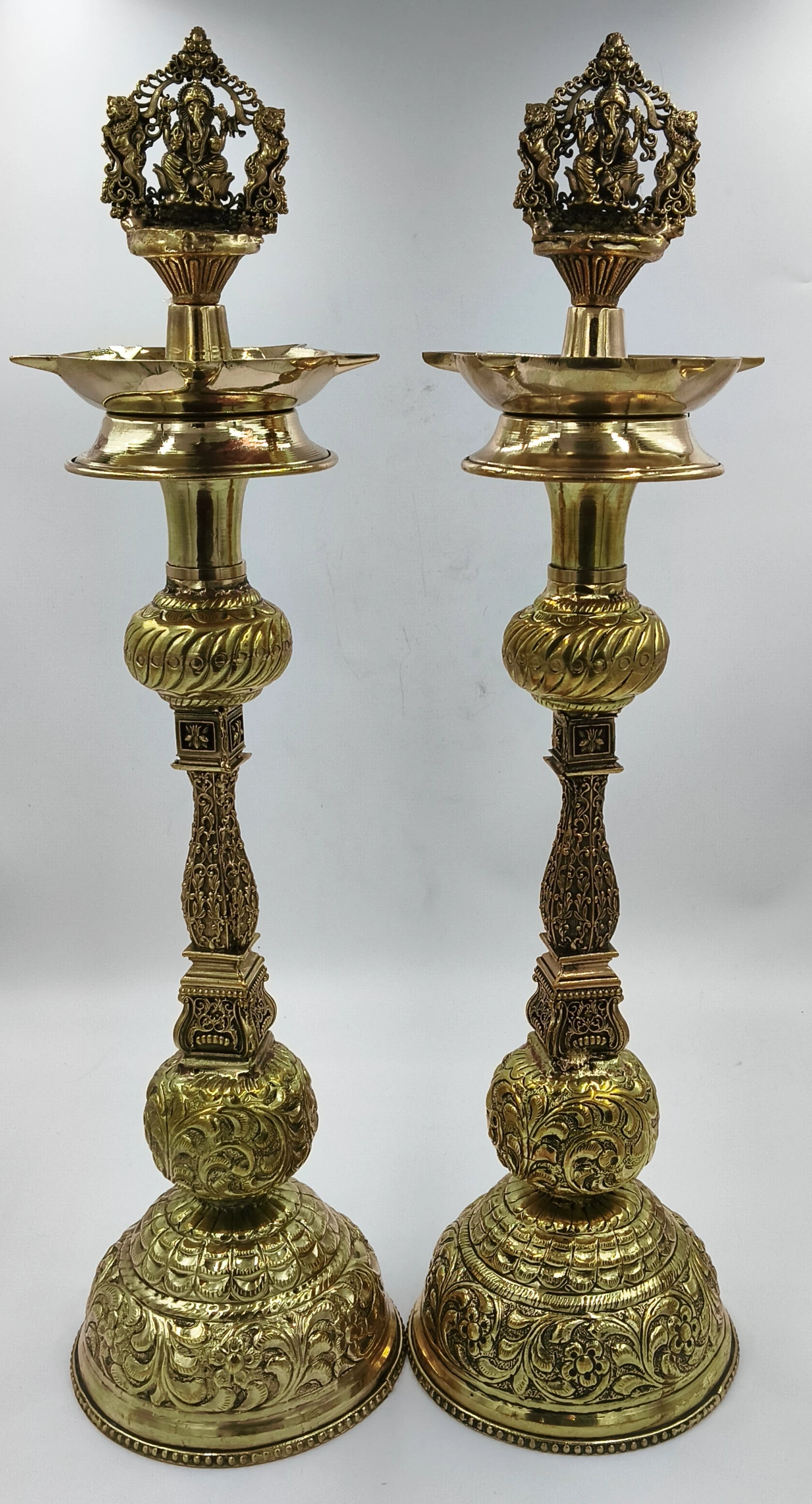 Pair of large ornate brass lamps with detailed carvings and Ganesha figure tops