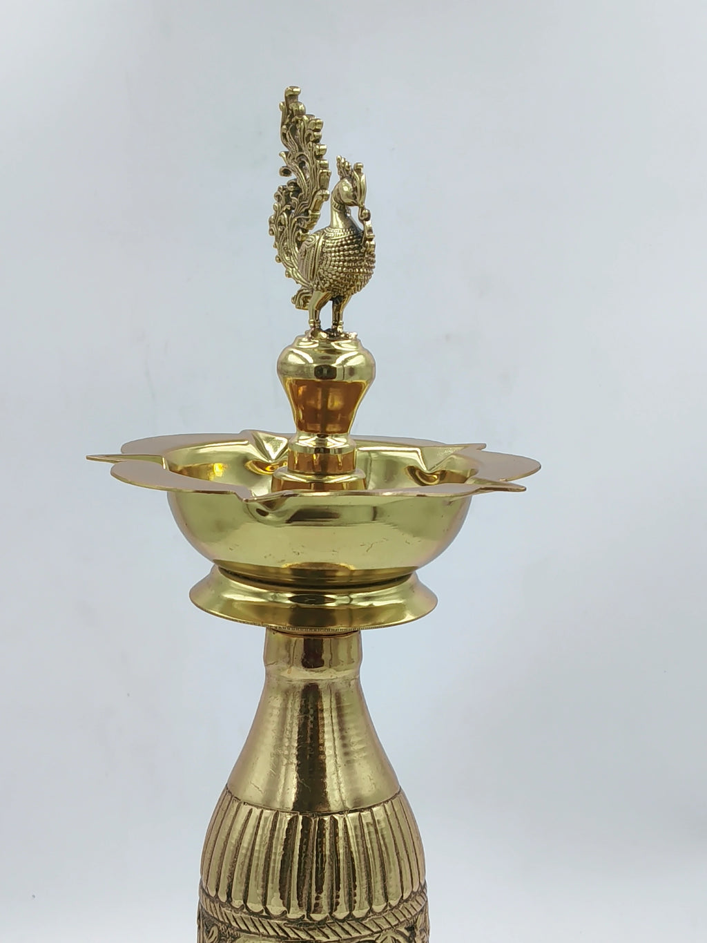 Large brass lamp with detailed peacock figure on top and decorative base