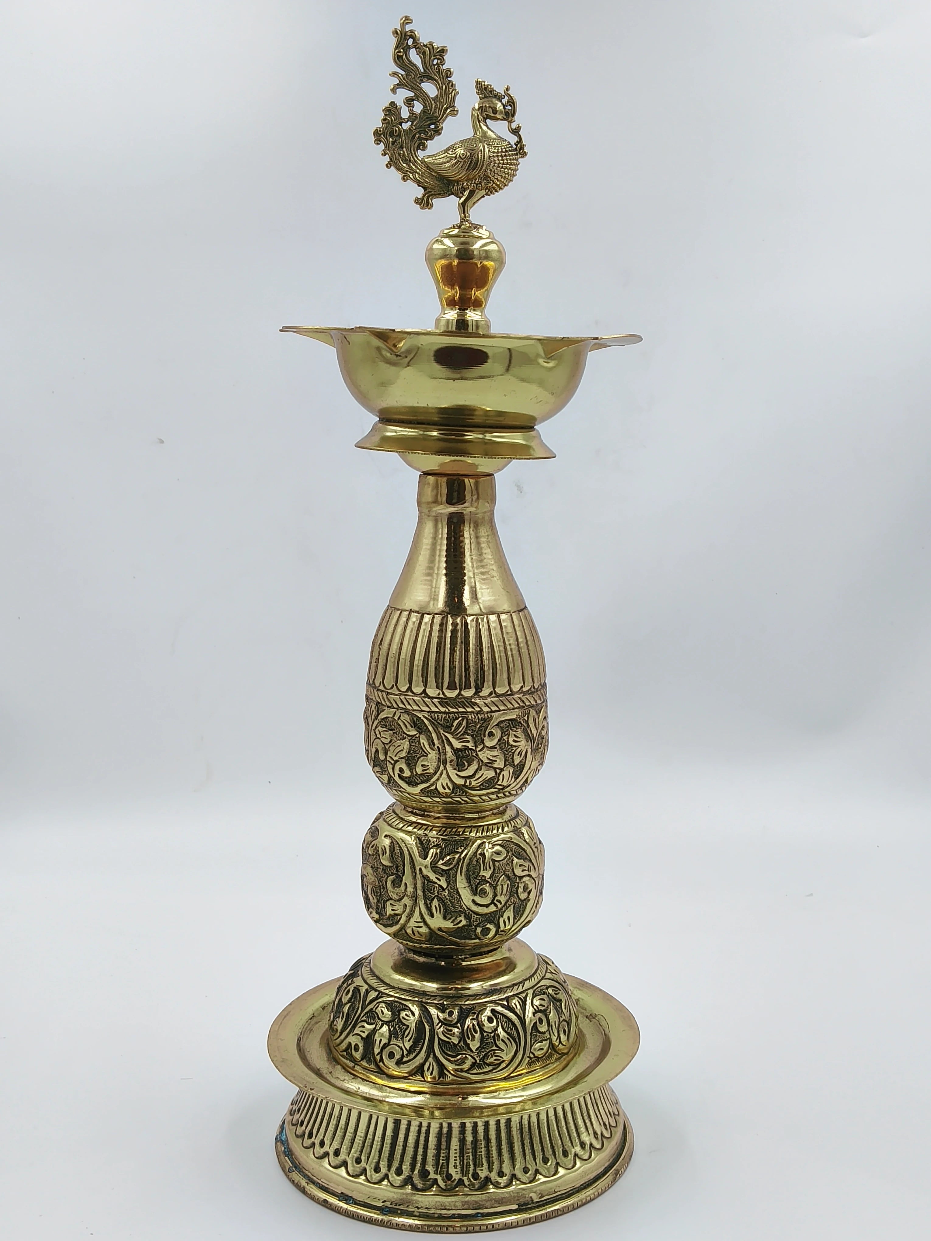 Tall traditional brass lamp with intricate engraved patterns and peacock finial