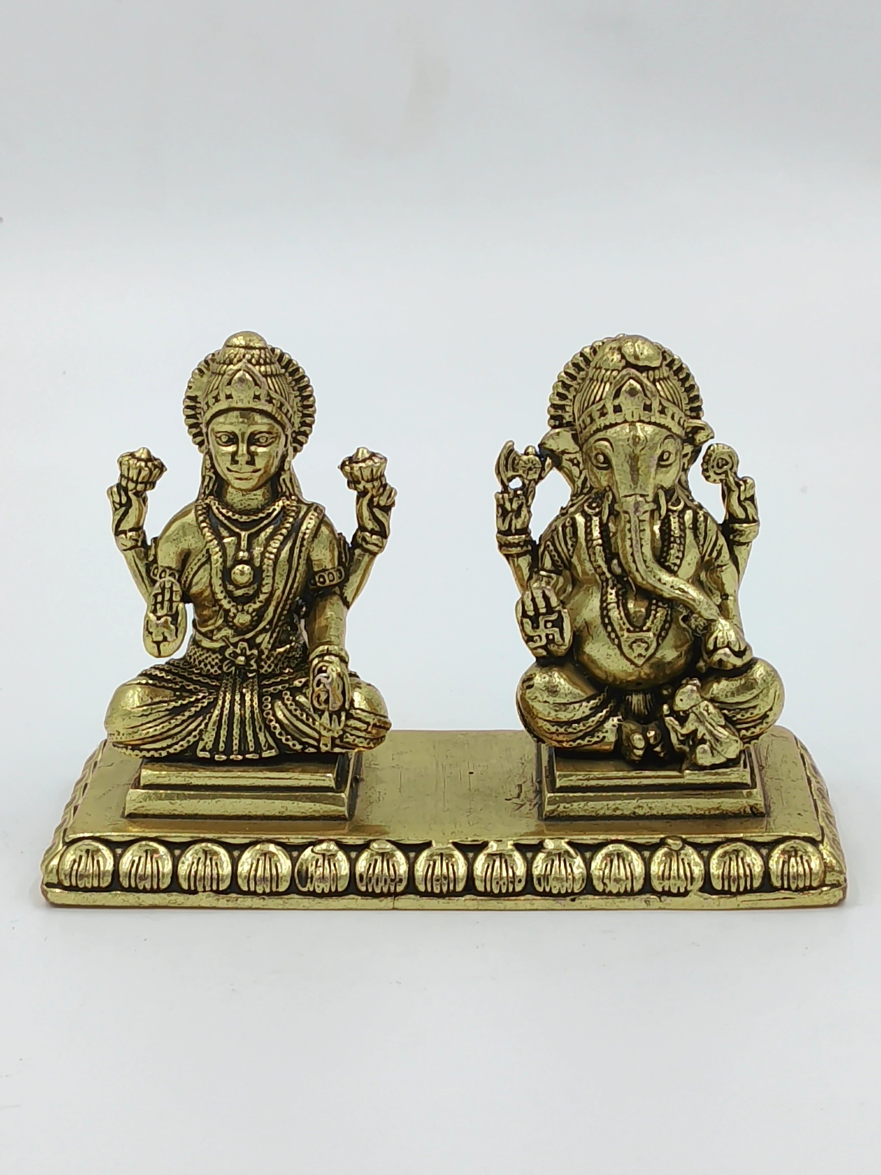 Small brass figurines of Lakshmi and Ganesh deities on a decorative base