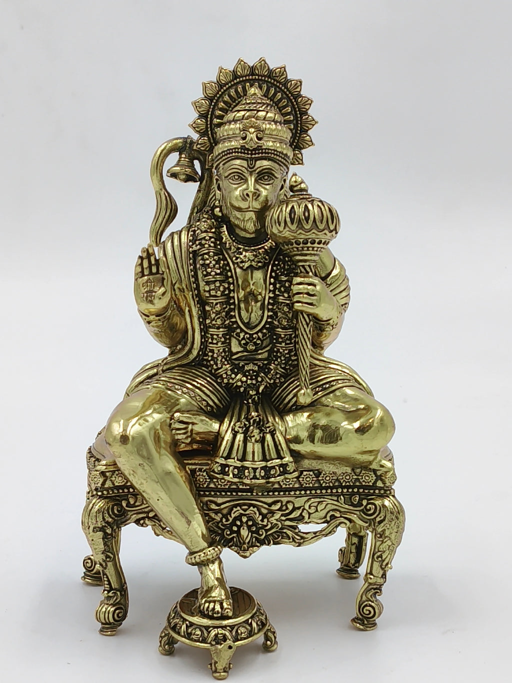 Brass statue of Hanuman sitting cross-legged on an ornate chowki