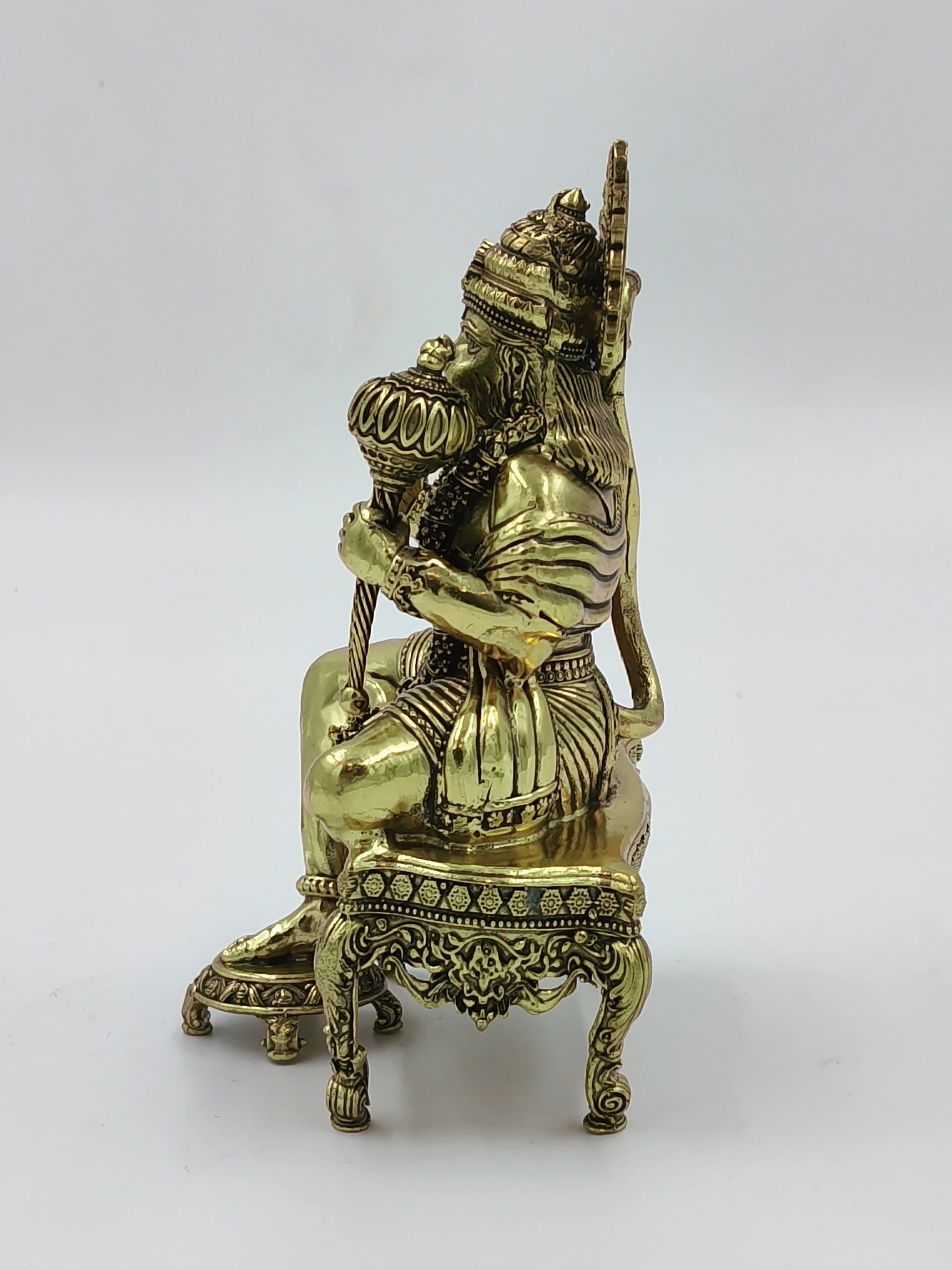 Side view of brass Hanuman statue sitting on an ornate chowki