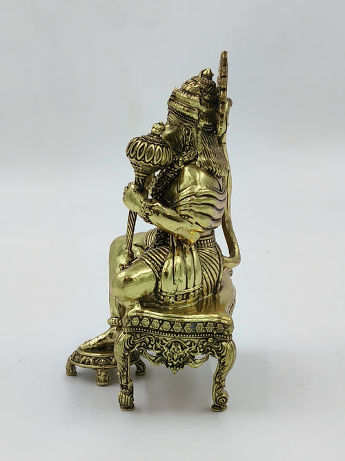 Side view of brass Hanuman statue sitting on an ornate chowki