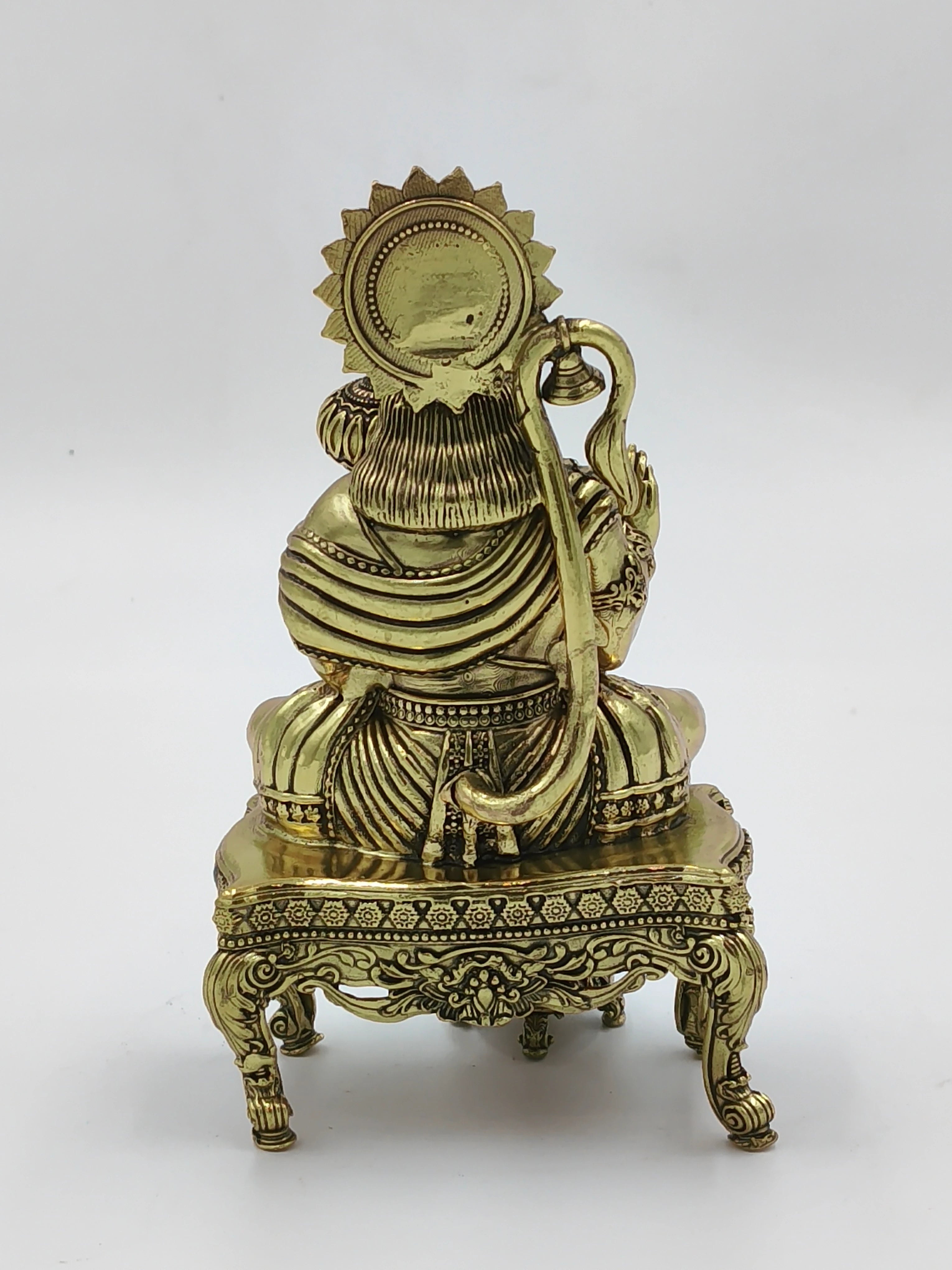 Back view of brass Hanuman figurine sitting on ornate chowki