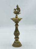 Tall brass lamp with intricate engravings and peacock design on top