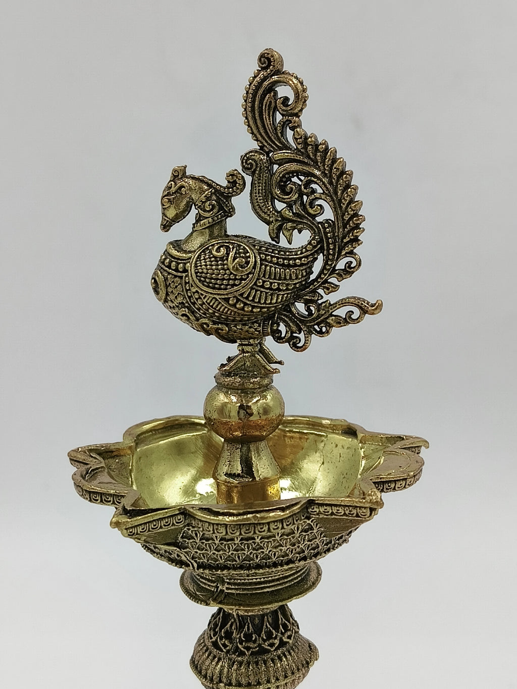 Ornate brass lamp with detailed bird figure and floral patterns