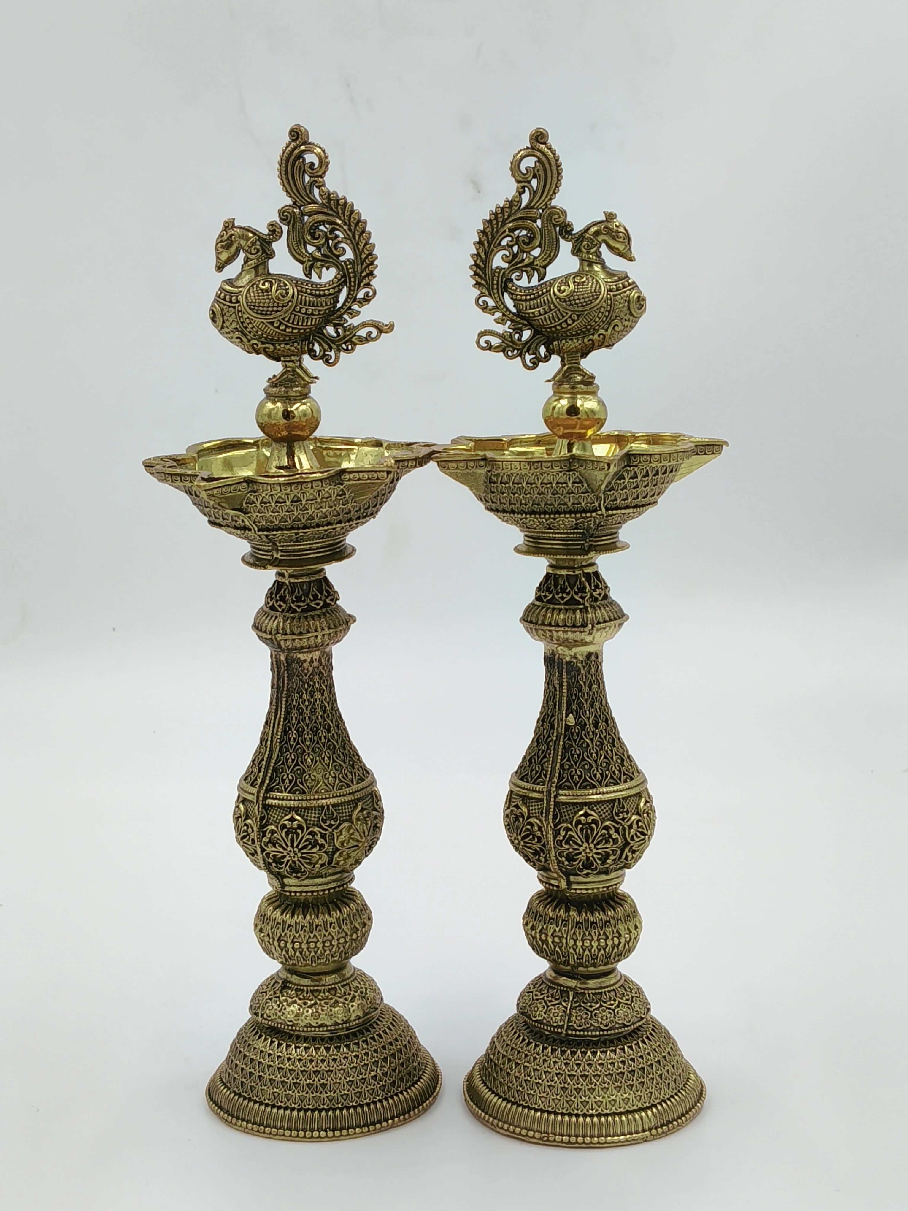 Pair of tall decorative brass lamps with intricate floral and peacock designs