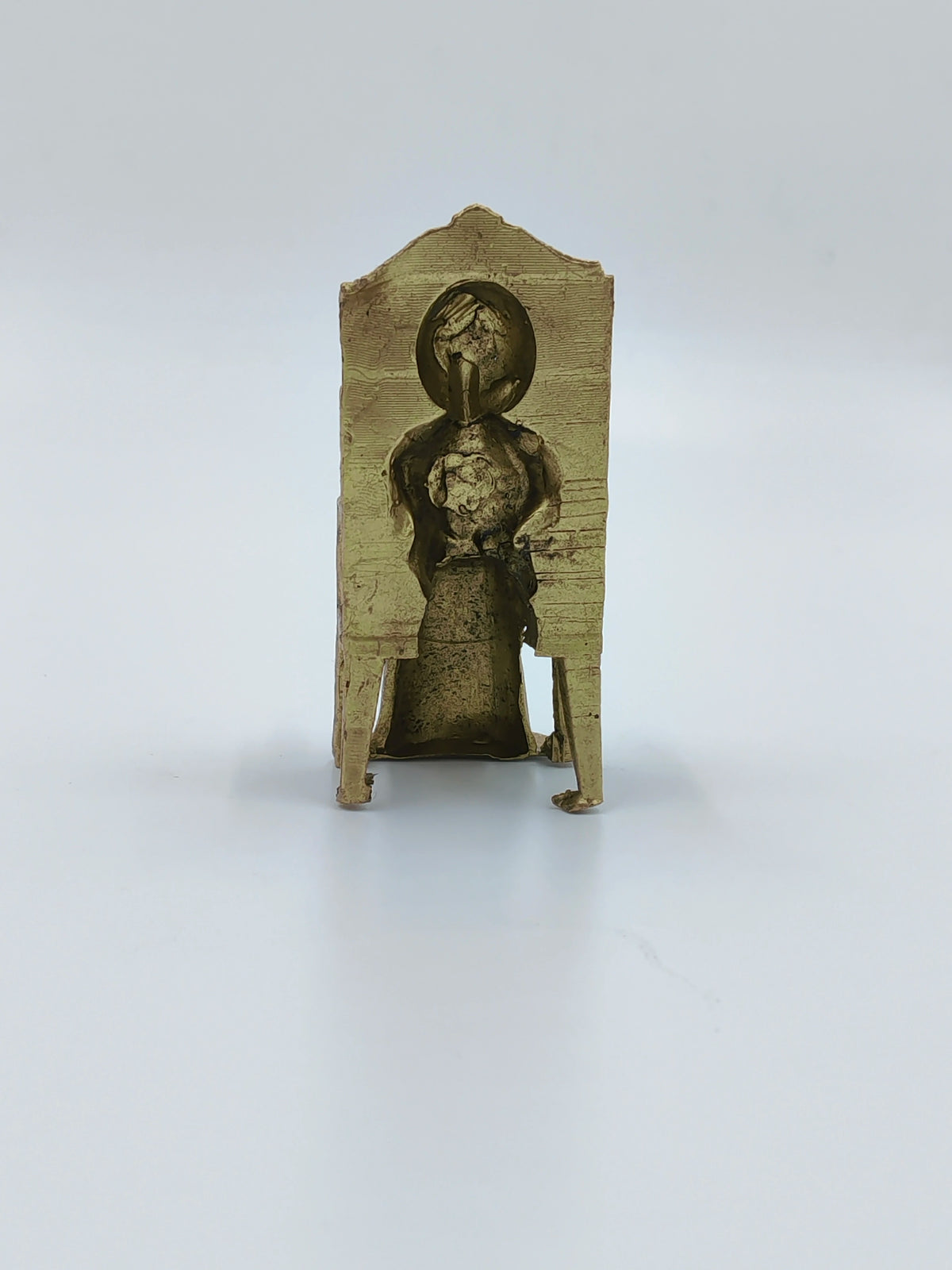 Back view of small brass Sai Baba sculpture sitting on a chair