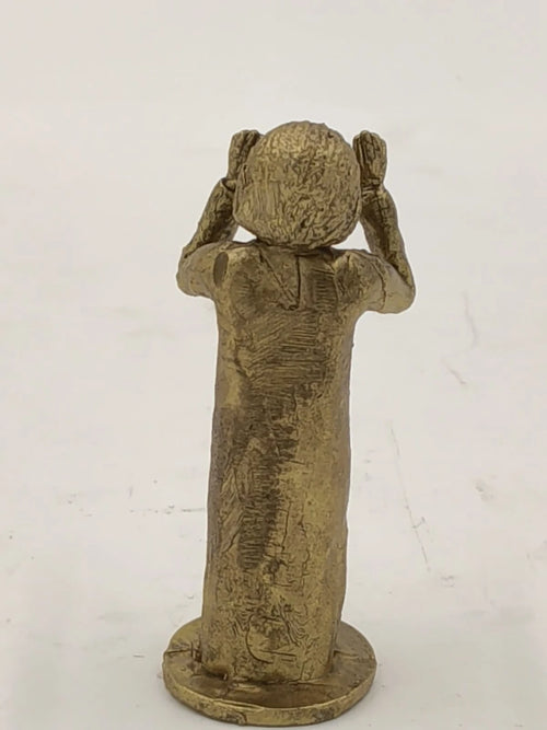 Back view of small brass Sai Baba figurine standing on a round base