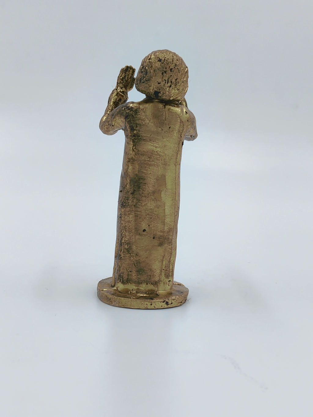 Back view of small brass Sai Baba figurine with raised hand