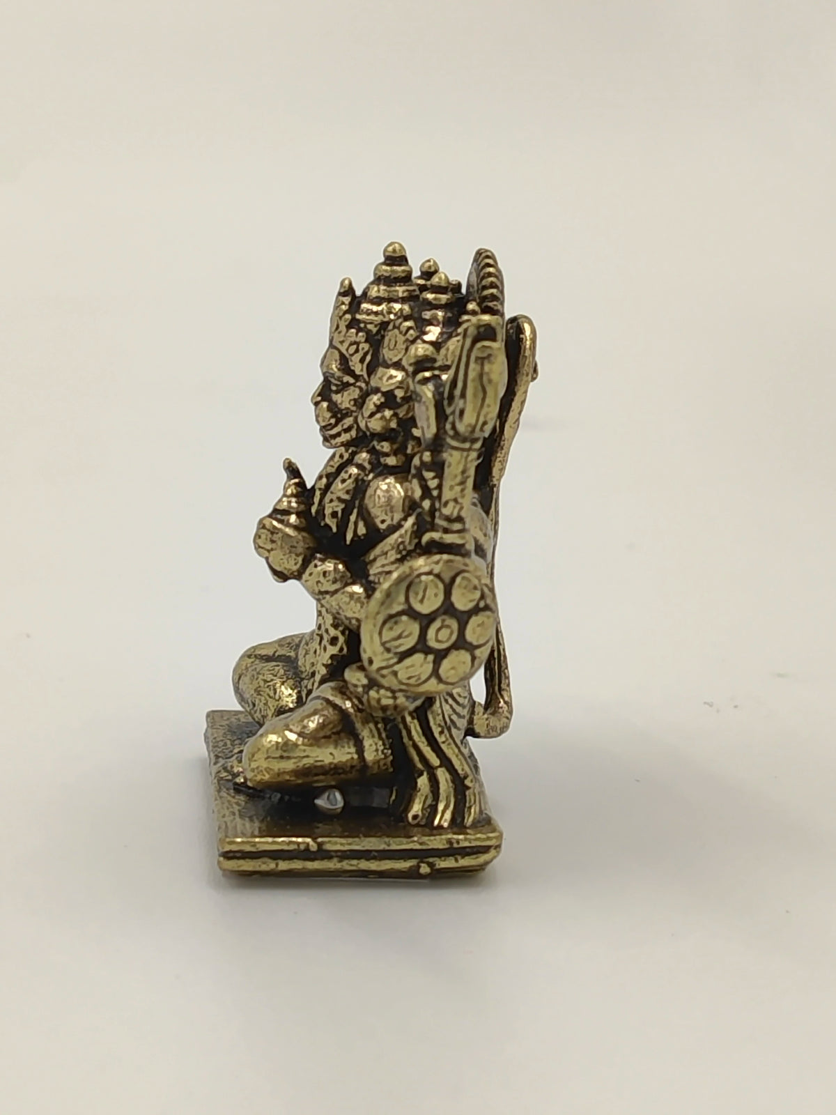 Side view of a mini brass Panchamukhi Hanuman statue sitting on a square base