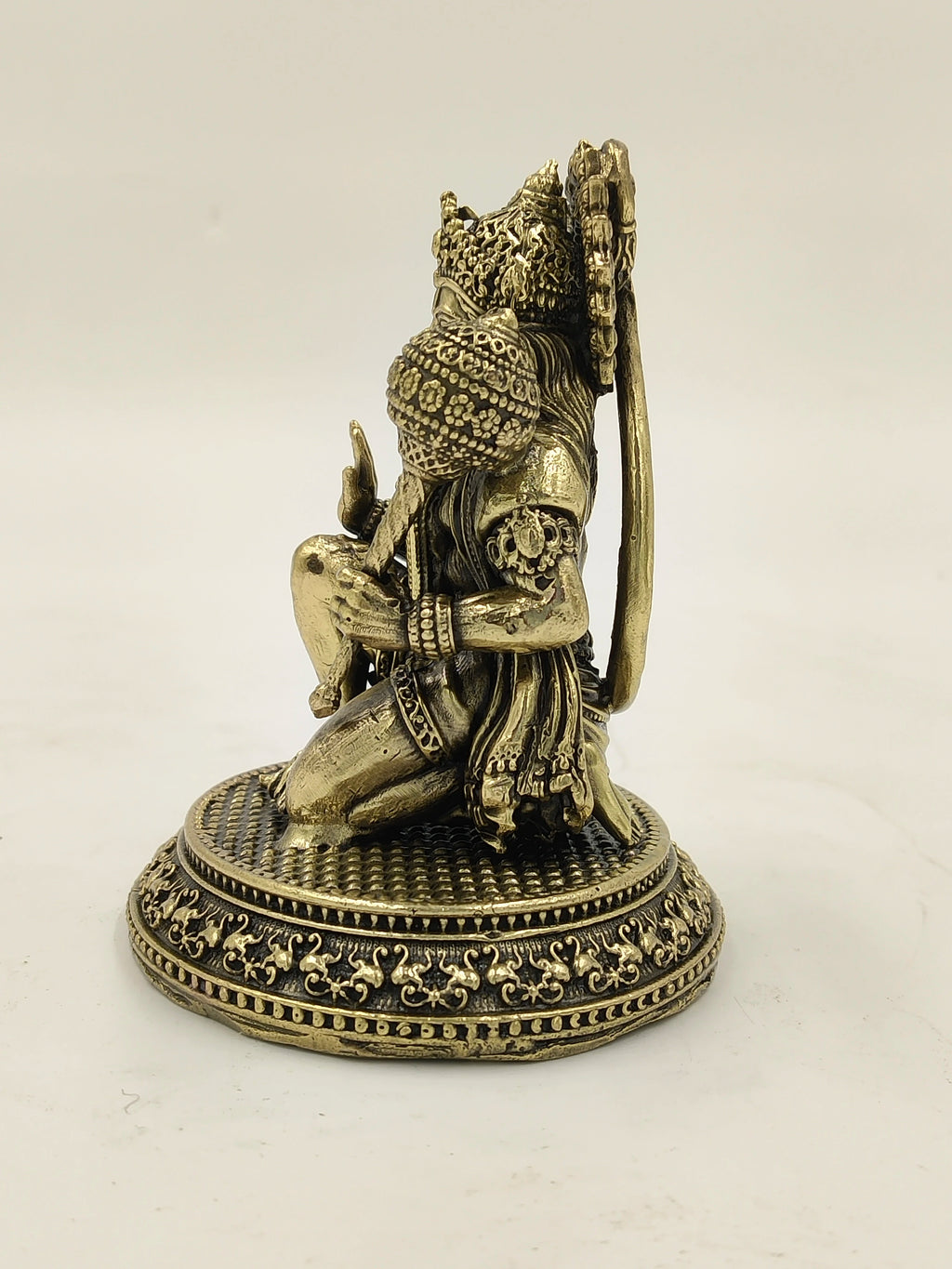 Small brass Hanuman statue kneeling on ornate round base side view