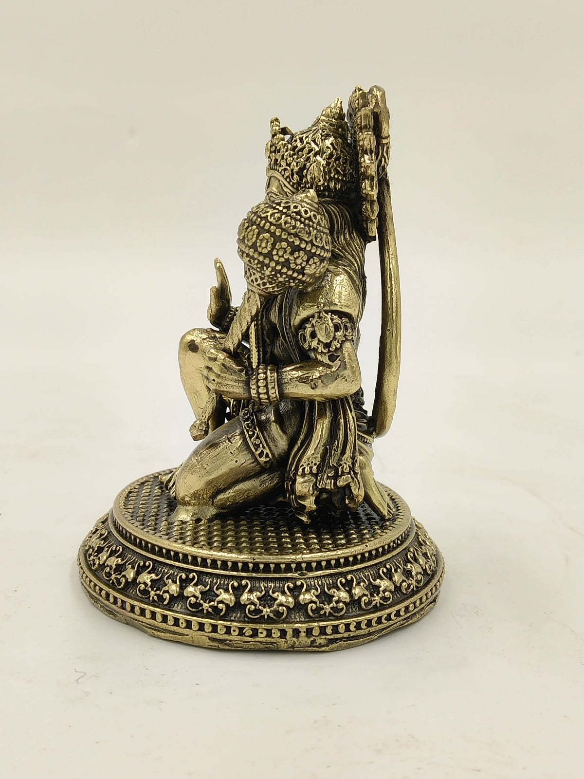 Small brass Hanuman statue kneeling on ornate round base side view