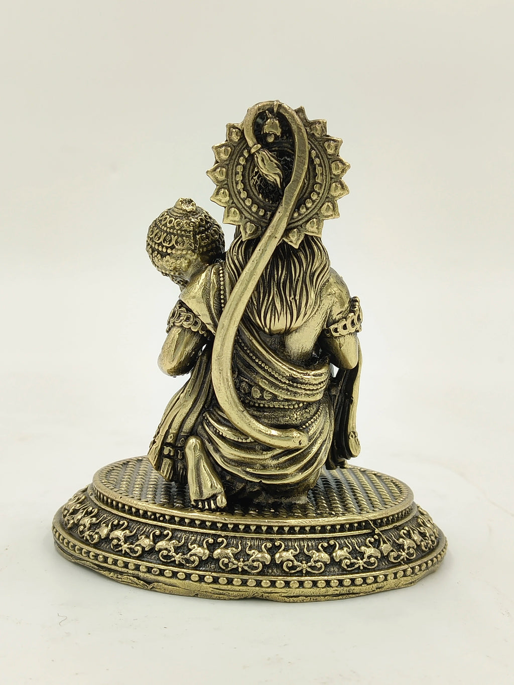 Back view of small brass Hanuman statue sitting on decorative round base