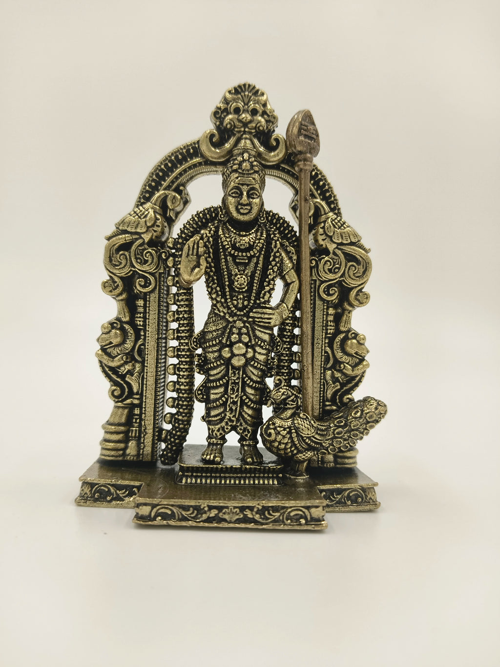 Small brass sculpture of deity Murgan with ornate arch and peacock
