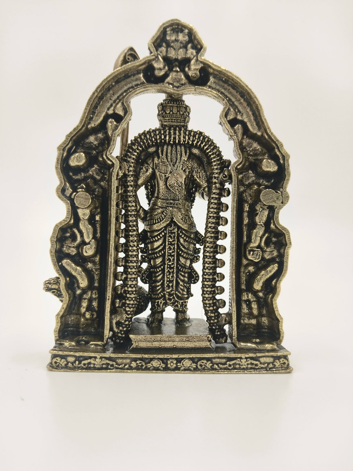 Back view of small brass Murgan sculpture with decorative arch frame