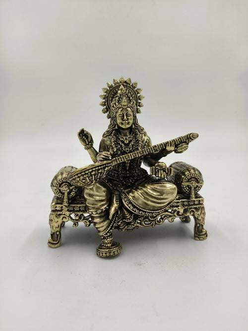 Small brass sculpture of Saraswathi sitting on a decorated chowki with veena