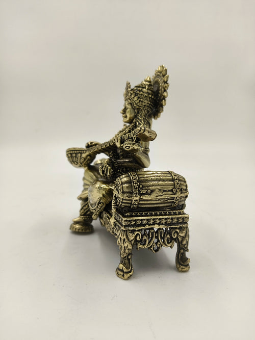 Brass statue of Saraswathi seated on an intricately designed chowki, side view