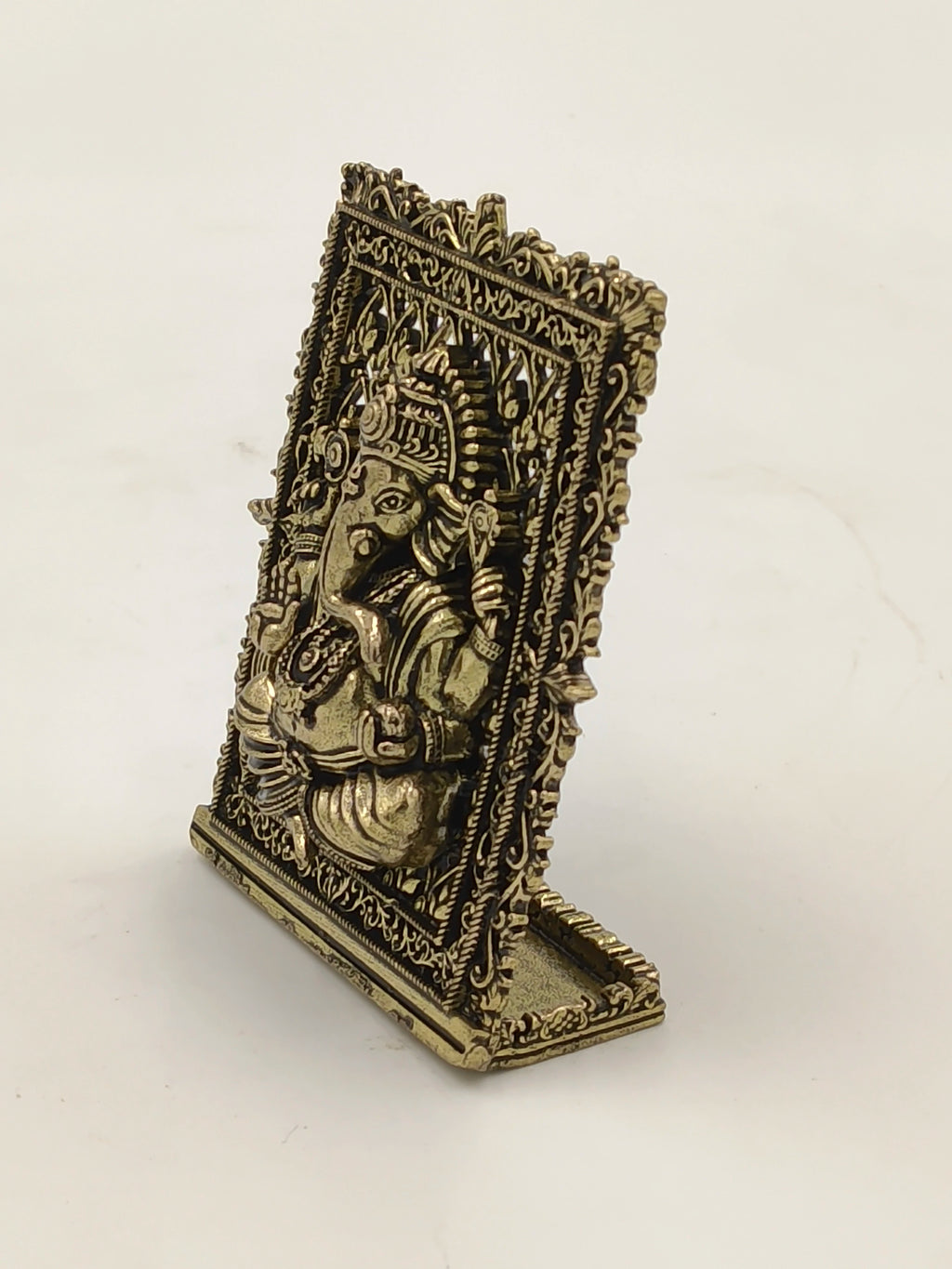 Small brass Ganesh panel sculpture with intricate borders, tabletop decor