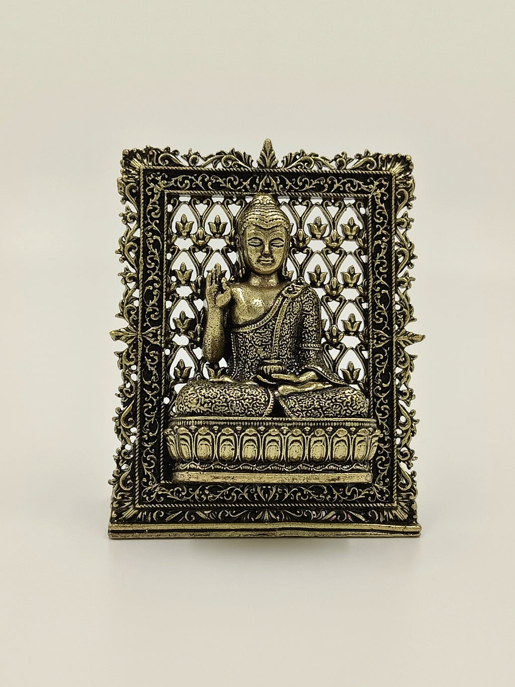 Small brass Buddha panel sculpture with ornate floral frame and lotus seat