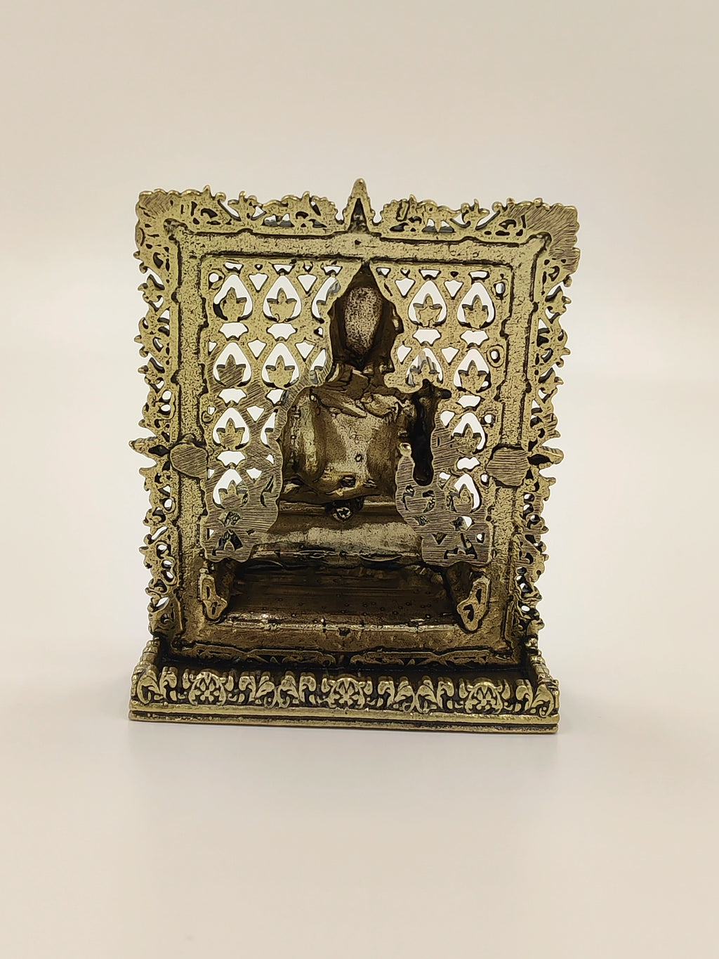 Small brass Buddha panel sculpture with intricate floral frame design