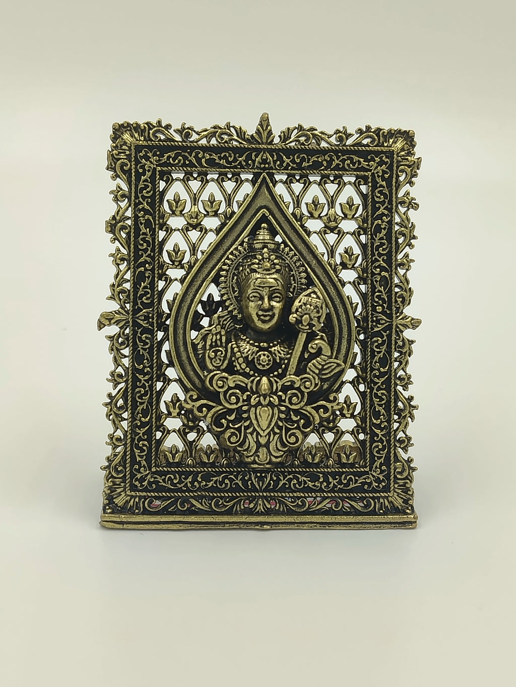 Small brass sculpture panel featuring deity Murgan with intricate floral frame
