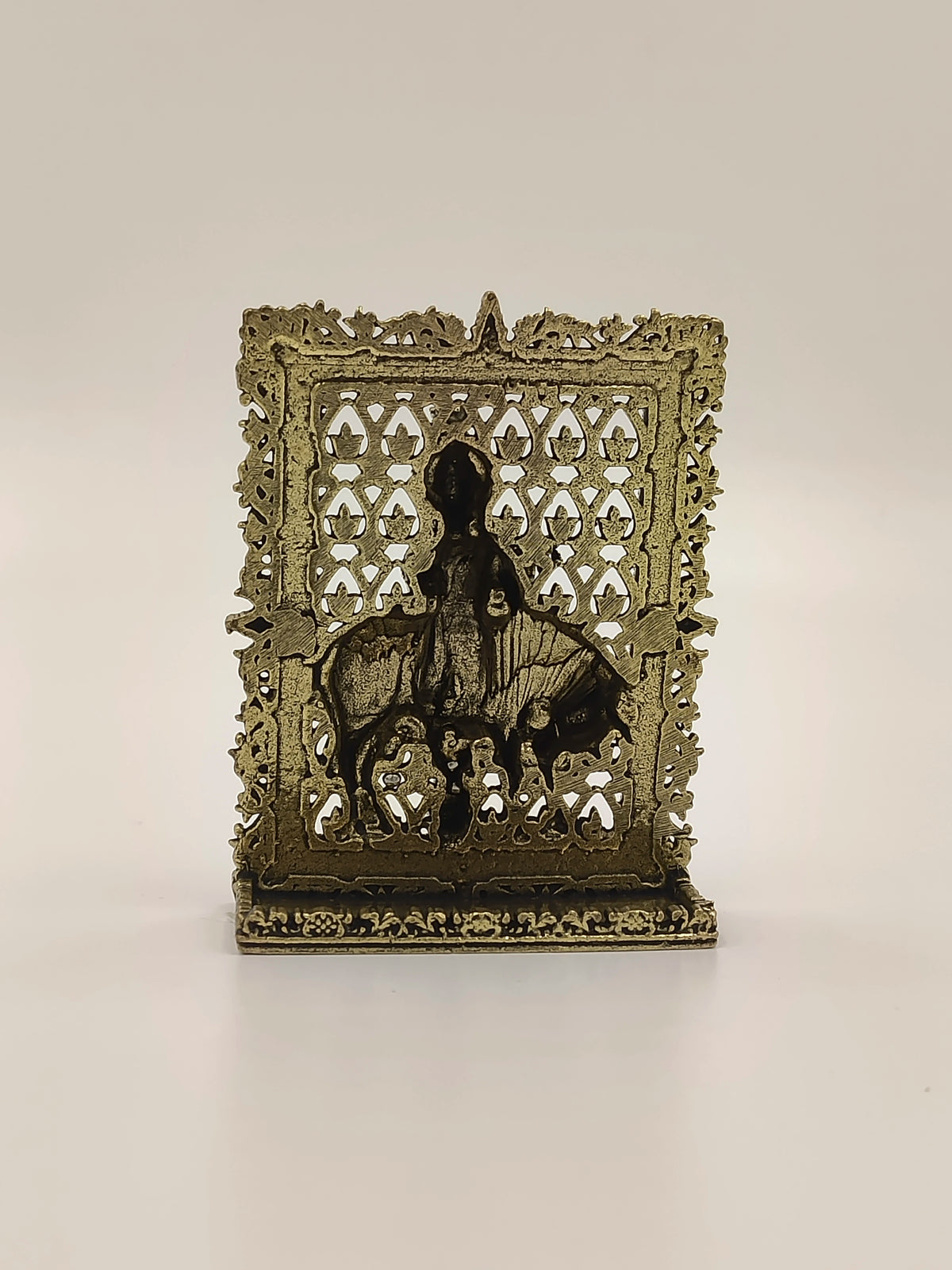 Small brass Krishna panel sculpture with ornate border and Krishna figure on bull