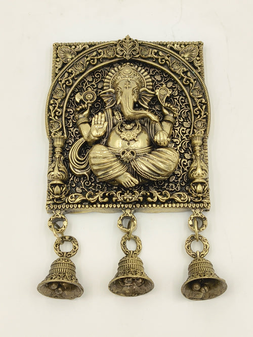 Large brass square frame featuring seated Ganesh with intricate floral details and three hanging bells