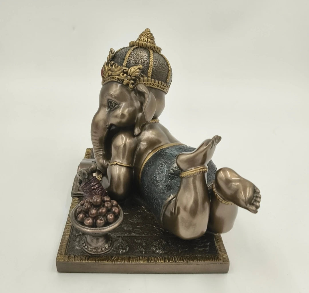 Side view of medium polyresin sculpture of playful Baby Ganesh lying on stomach