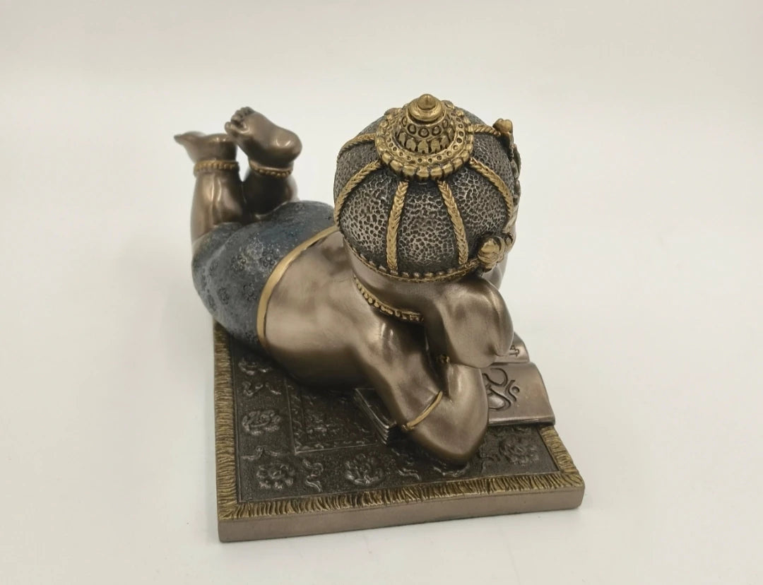 Polyresin sculpture of playful Baby Ganesh lying on stomach on a textured base