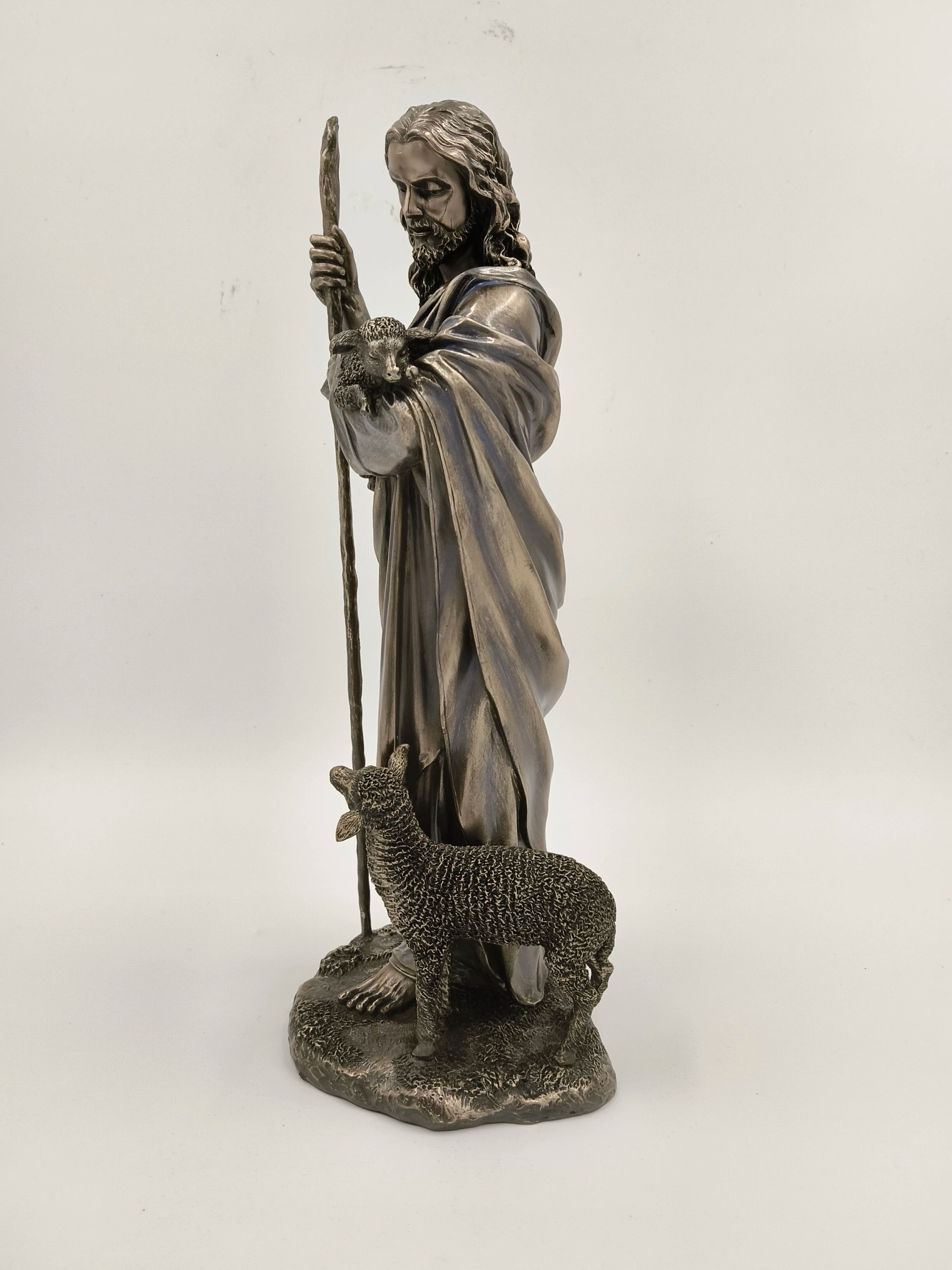 Polyresin sculpture of Jesus Christ holding a staff with a lamb on his arm and another lamb at his feet