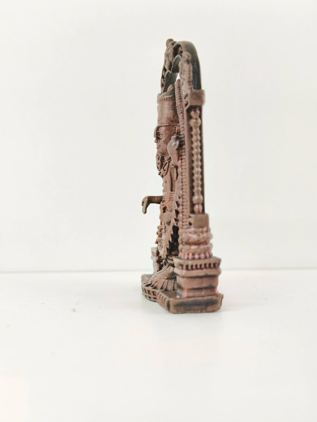 Side view of mini copper Balaji statue with detailed arch frame