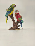 Brass enamel sculpture of two colorful parrots perched on a brown branch
