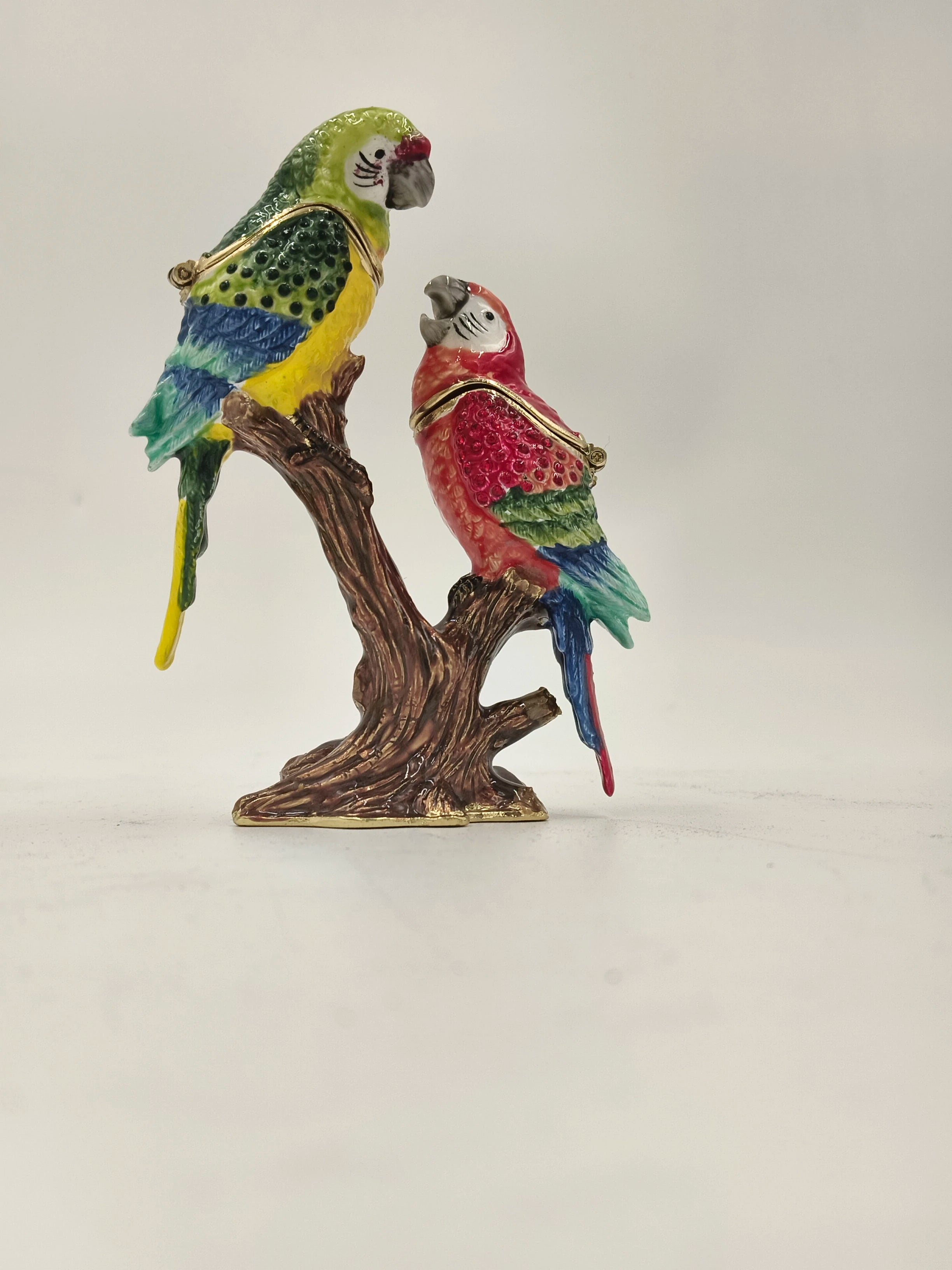 Brass enamel sculpture of two colorful parrots perched on a brown branch