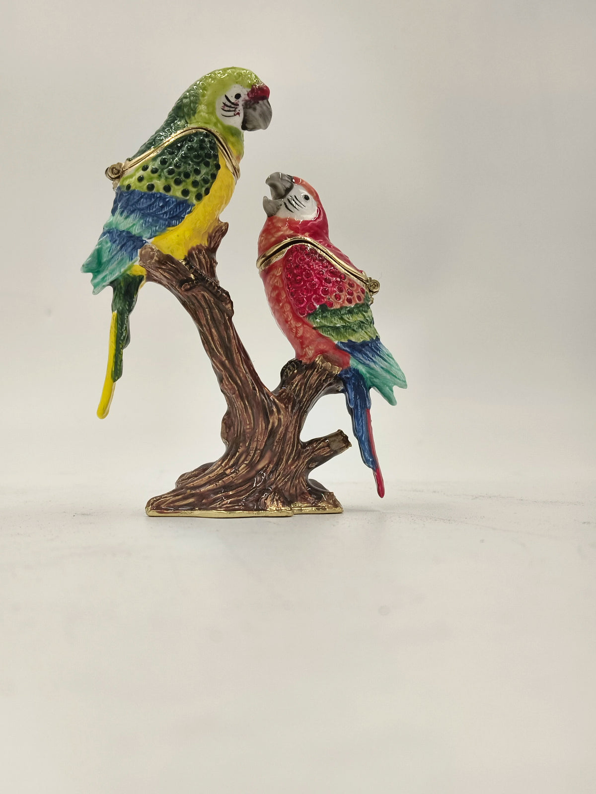 Brass enamel sculpture of two colorful parrots perched on a brown branch