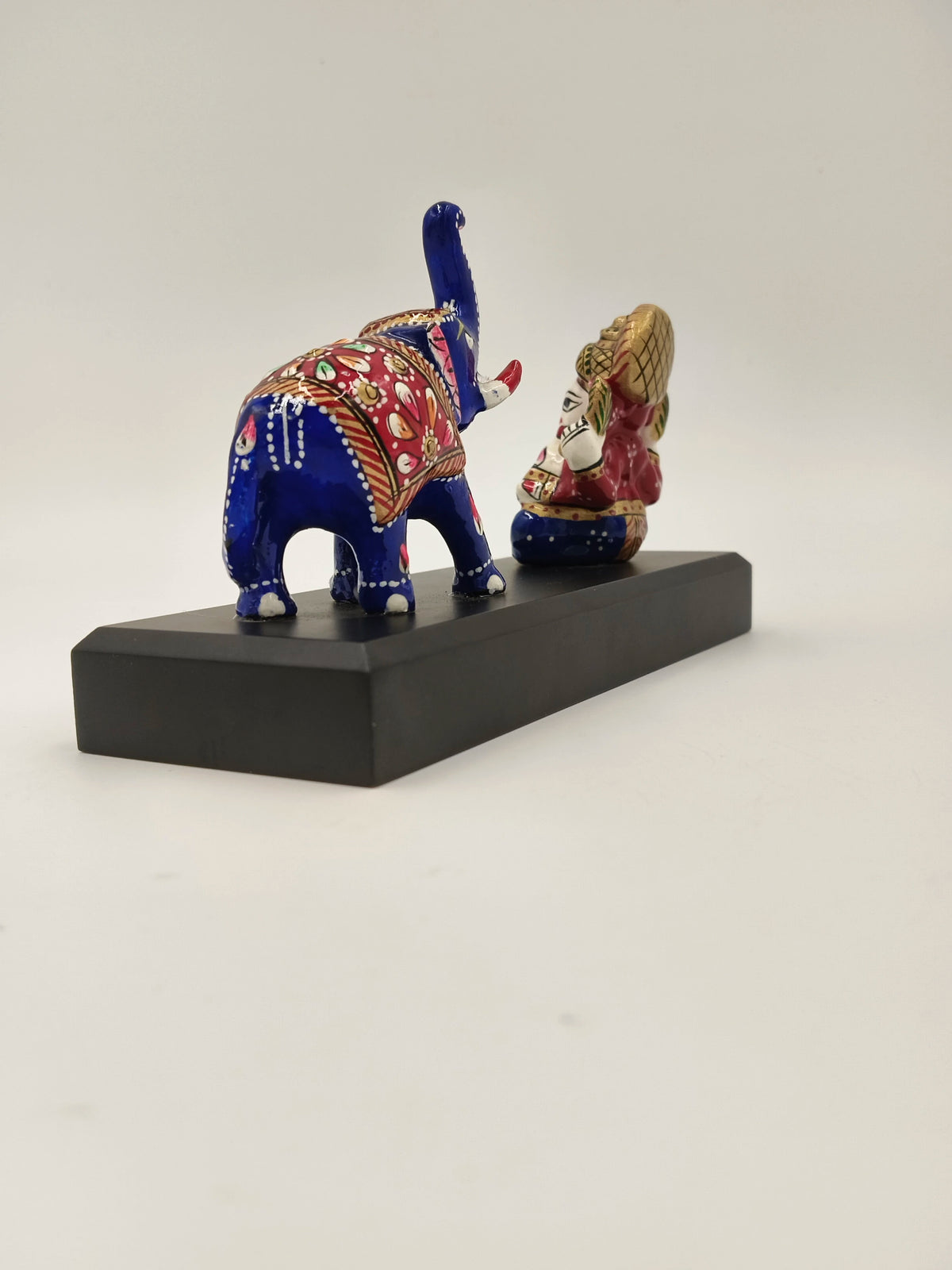 Small brass Ganesh statue with blue decorative elephant on black base side view
