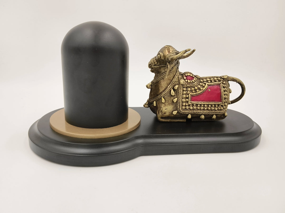 Brass Nandhi sculpture with red accents beside black Shivling on black base
