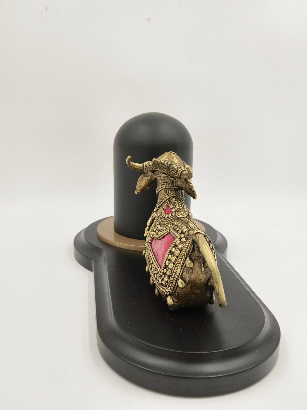 Brass Nandhi figurine with decorative details beside black Shivling on base