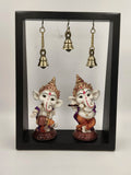 Black frame with two musical brass Ganesha idols and three hanging brass bells