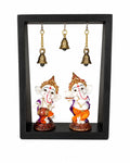 Black frame with two musical brass Ganesha idols and three hanging brass bells