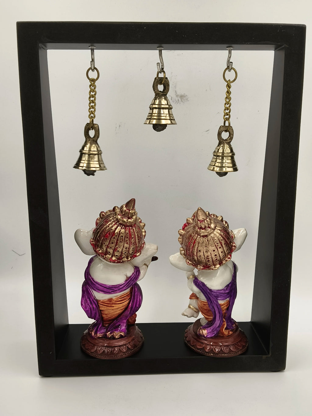 Back view of brass musical Ganesha figurines framed and hanging bells