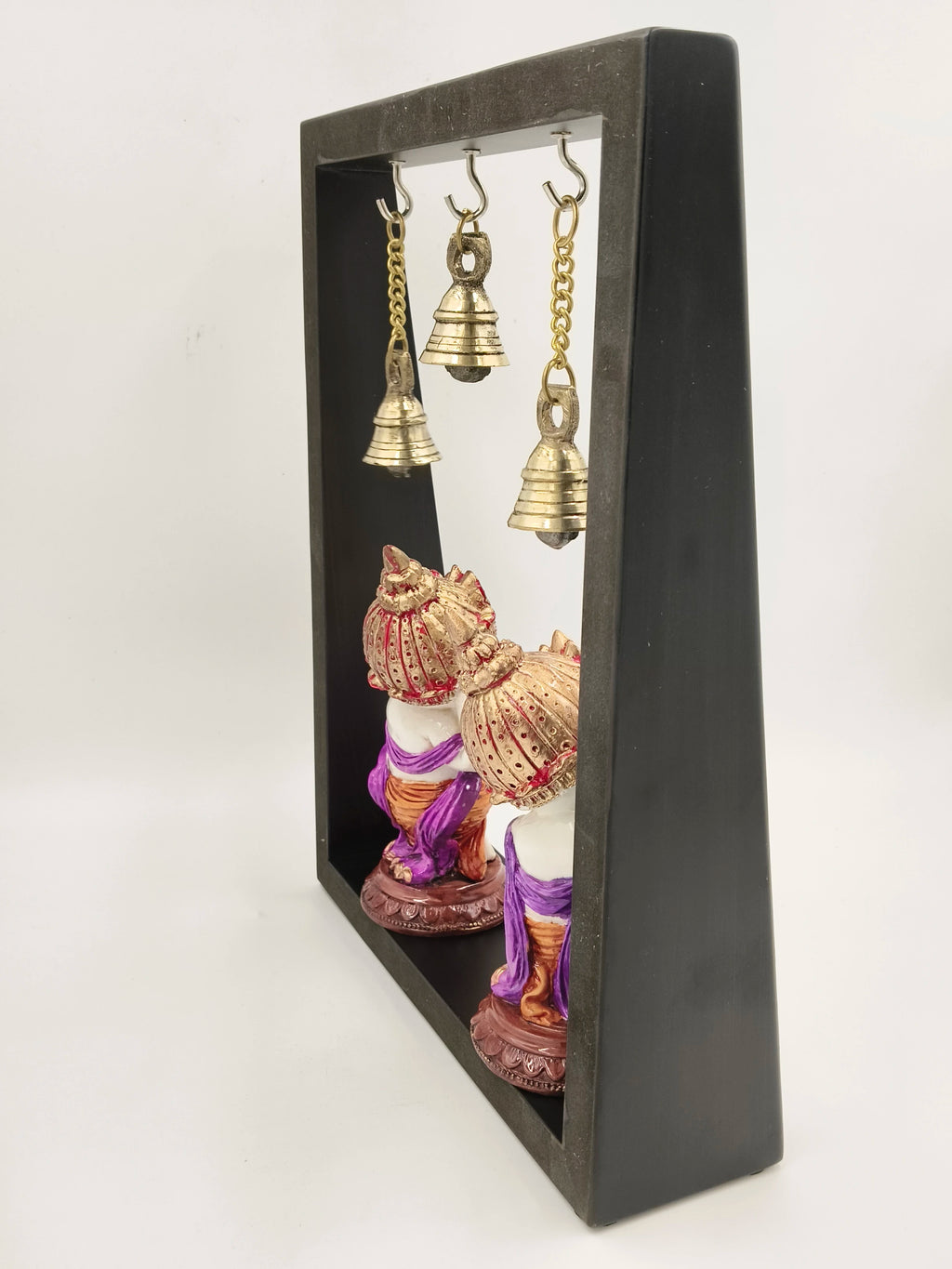 Side view of large brass musical Ganesha sculpture framed with three hanging brass bells