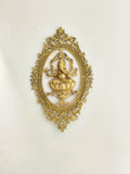 large brass wall hanging featuring Ganesh seated on lotus with ornate oval frame