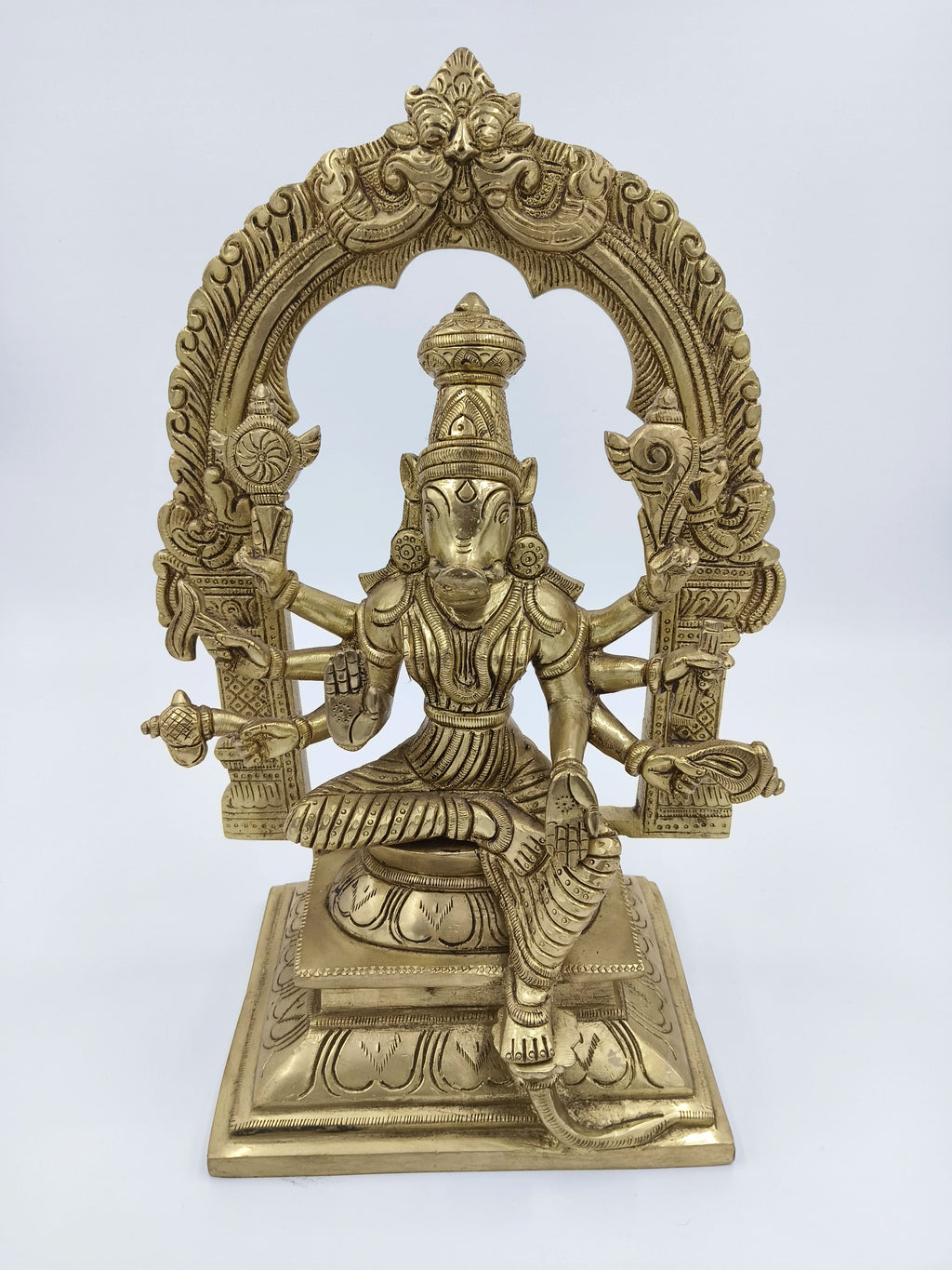 Large brass sculpture of Goddess Varahi seated with multiple arms under an ornate arch