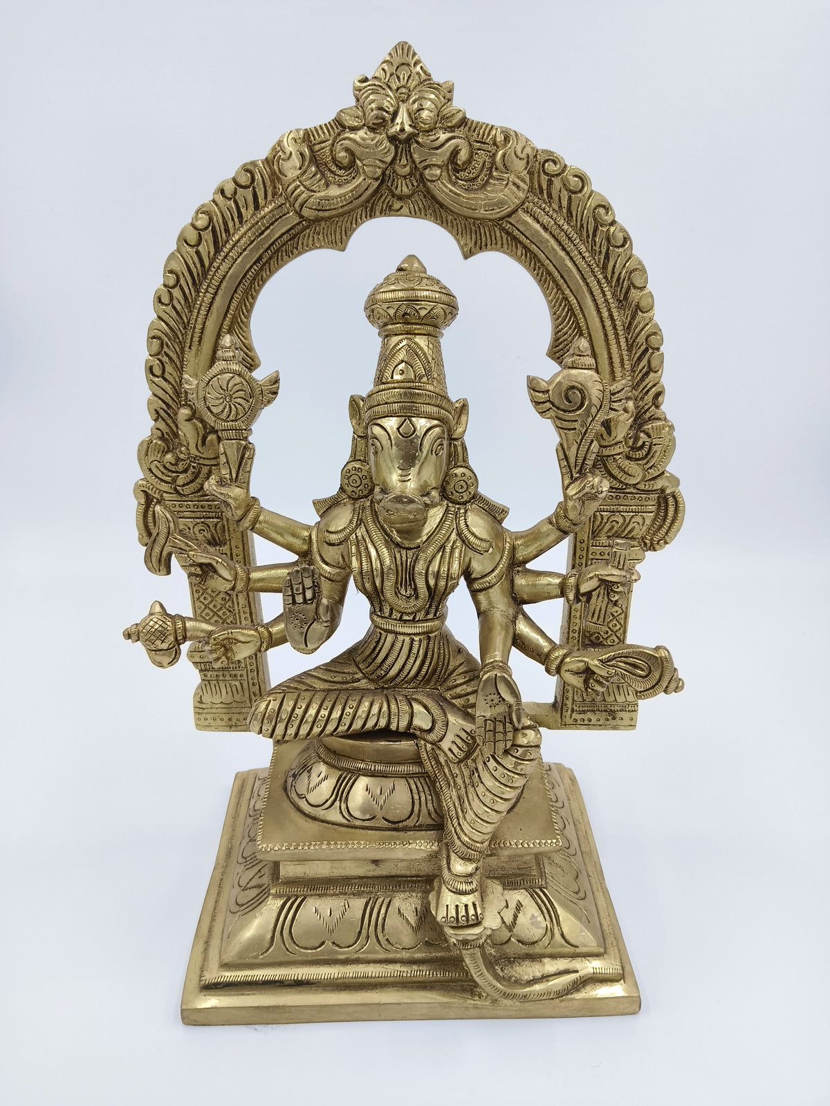 Large brass sculpture of Goddess Varahi seated with multiple arms under an ornate arch